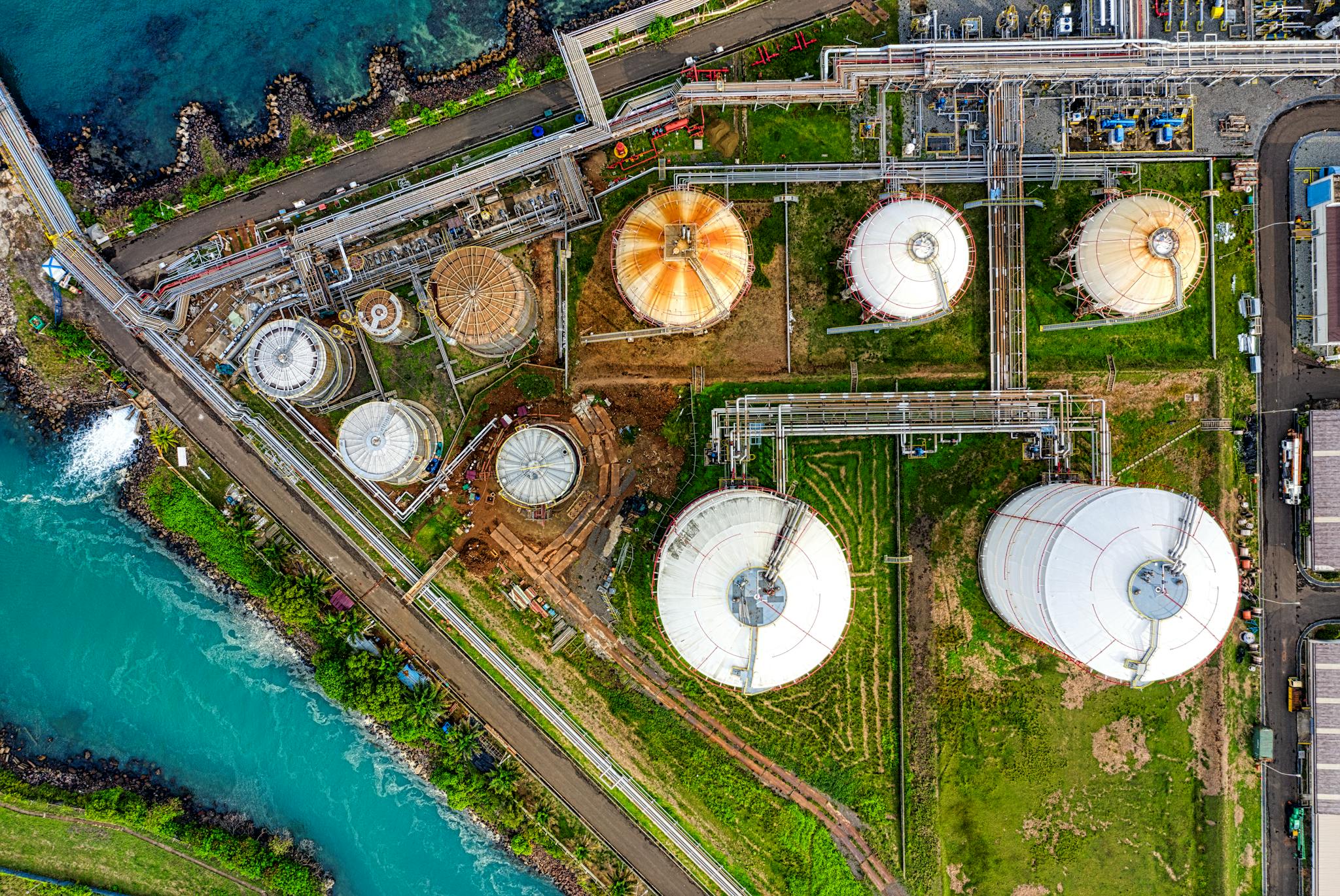 Aerial view of an industrial complex near a river in Banten, Indonesia, showcasing storage tanks.
